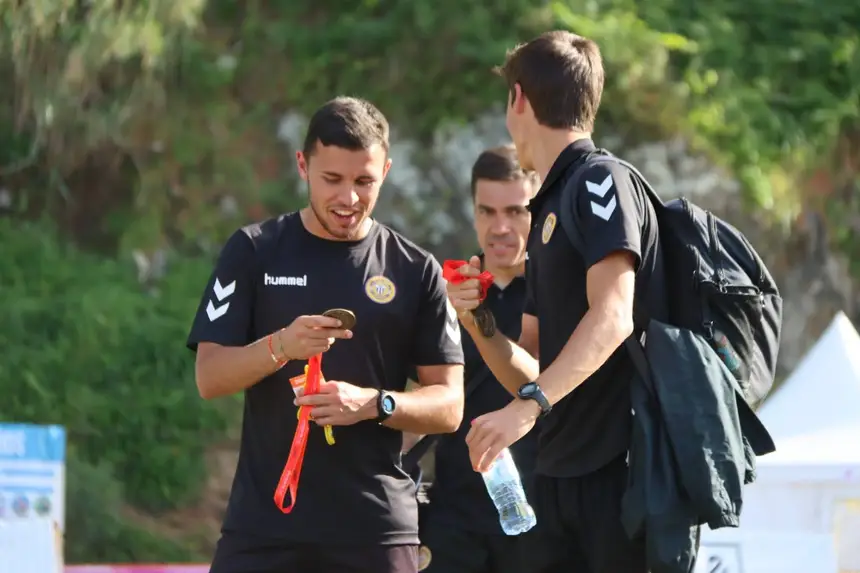Equipa técnica a conversar à beira do campo antes do treino, com os pratos de marcação na mão.